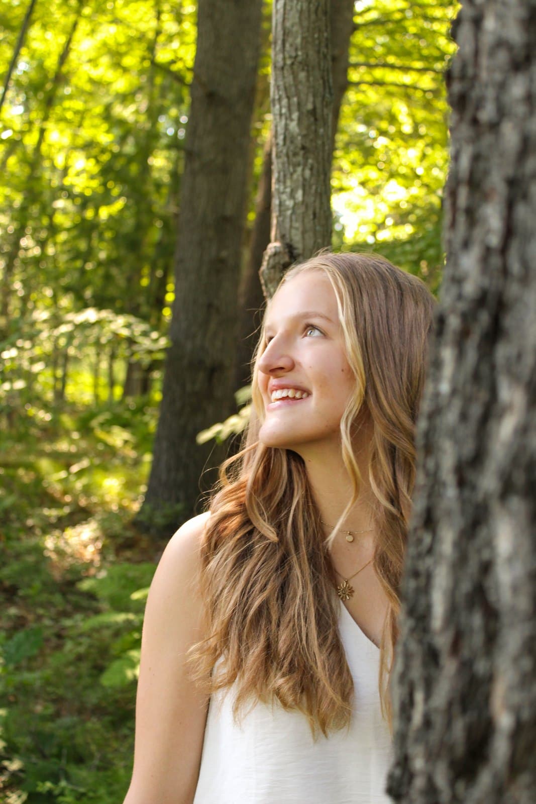 Senior portrait leaning against a tree in the woods